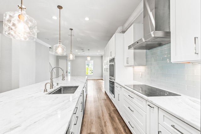 kitchen with black electric cooktop, sink, wall chimney range hood, hardwood / wood-style flooring, and white cabinets