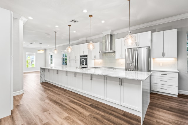 kitchen with stainless steel refrigerator with ice dispenser, white cabinetry, wall chimney exhaust hood, and a large island