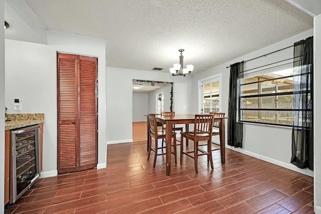 dining area featuring dark wood-style floors, visible vents, a chandelier, beverage cooler, and baseboards