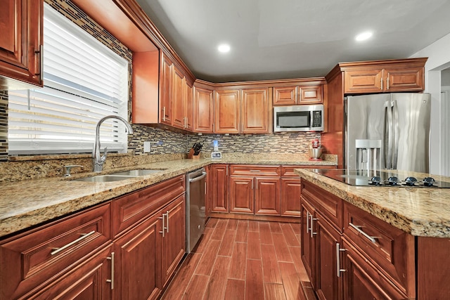 kitchen with light stone countertops, decorative backsplash, stainless steel appliances, and a sink