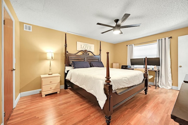 bedroom featuring baseboards, visible vents, a ceiling fan, a textured ceiling, and light wood-type flooring