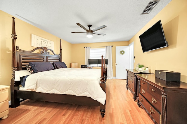 bedroom featuring visible vents, ceiling fan, light wood-style flooring, and a textured ceiling