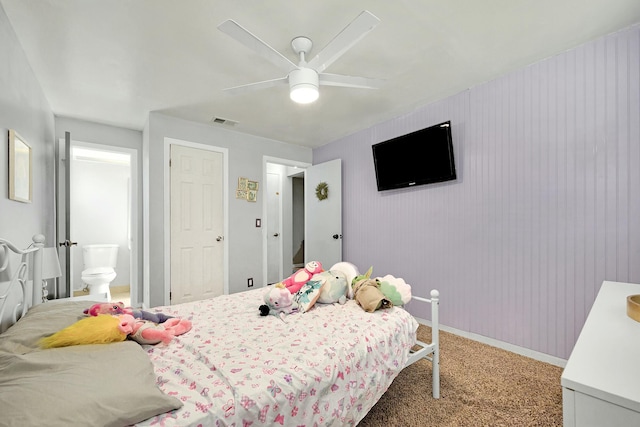 carpeted bedroom featuring baseboards, ensuite bath, visible vents, and a ceiling fan