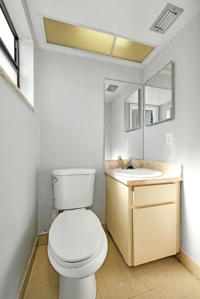 bathroom with toilet, vanity, and visible vents