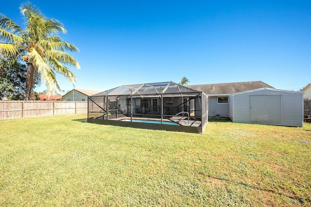 back of house featuring an outbuilding, a lawn, a storage shed, a lanai, and a fenced backyard