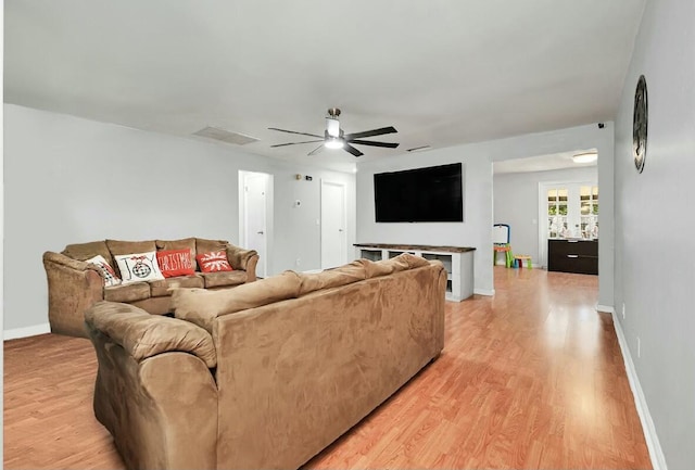 living area featuring ceiling fan, light wood finished floors, and baseboards