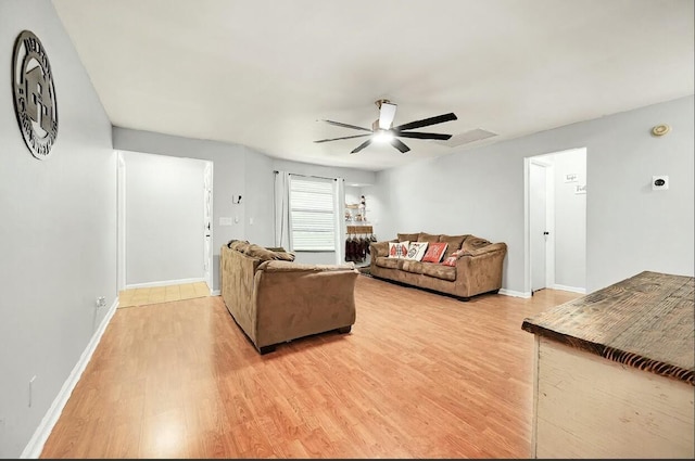 living area featuring ceiling fan, light wood-style flooring, and baseboards