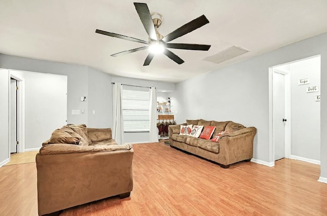 living room with light wood finished floors, attic access, visible vents, baseboards, and a ceiling fan