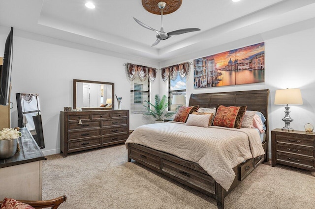 bedroom featuring light carpet, a raised ceiling, and ceiling fan