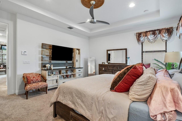 carpeted bedroom featuring a tray ceiling and ceiling fan