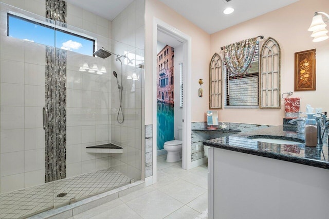 bathroom featuring tile patterned flooring, vanity, a tile shower, and toilet