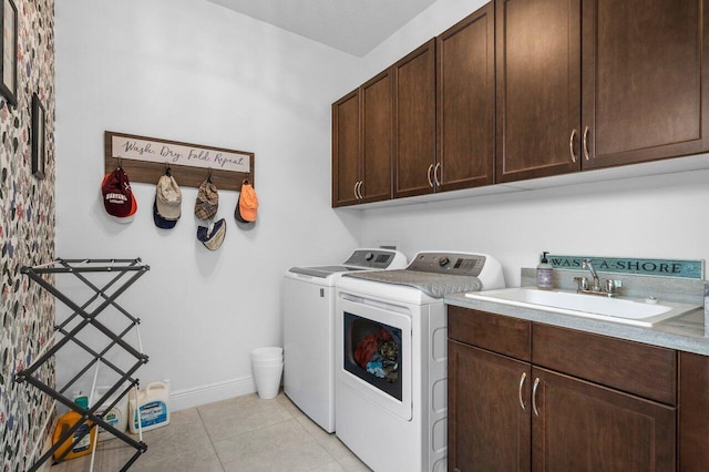 laundry room with light tile patterned flooring, cabinets, sink, and washing machine and clothes dryer