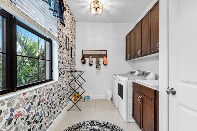 clothes washing area featuring cabinets, washer and clothes dryer, and light tile patterned floors