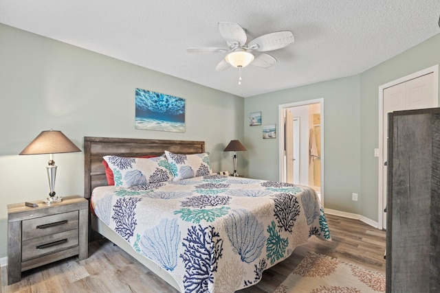 bedroom with a textured ceiling, connected bathroom, hardwood / wood-style flooring, and ceiling fan