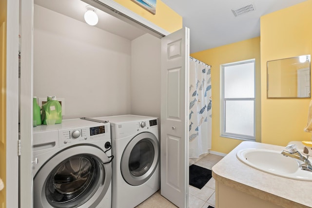 washroom featuring light tile patterned flooring, washing machine and dryer, and sink