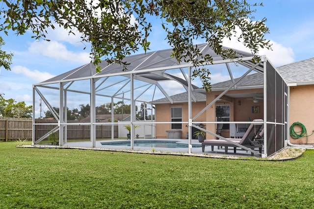 rear view of house with a lawn, a lanai, and a fenced in pool