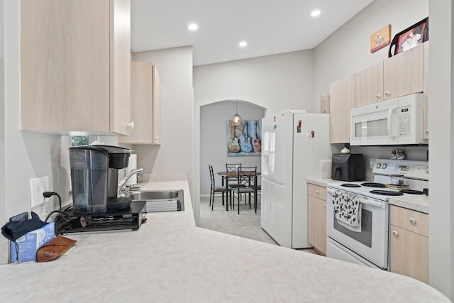 kitchen with light tile patterned floors, white appliances, sink, and light brown cabinetry