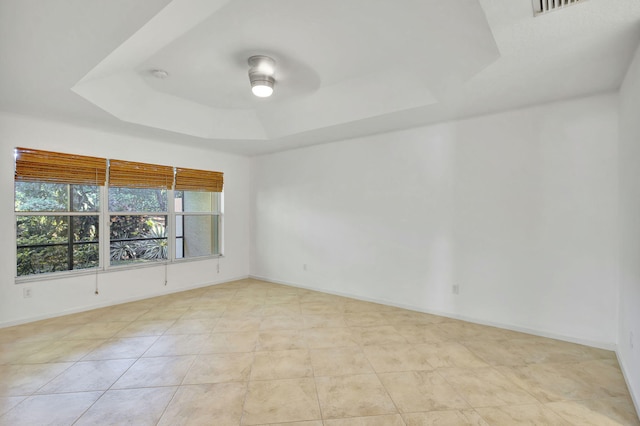 tiled spare room featuring a raised ceiling