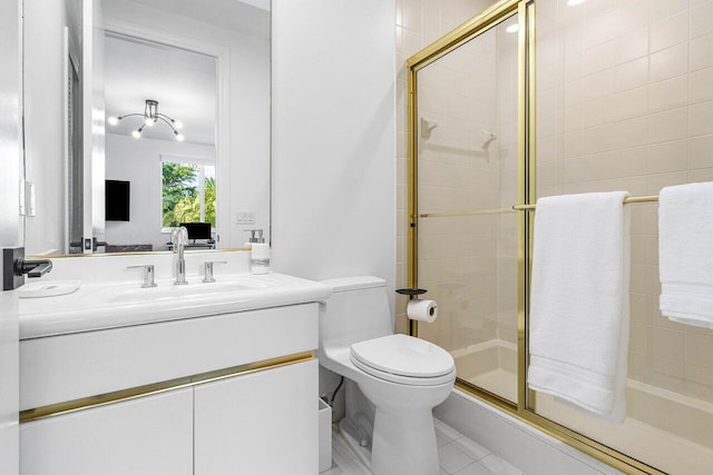 bathroom featuring tile patterned floors, vanity, toilet, and a shower with shower door