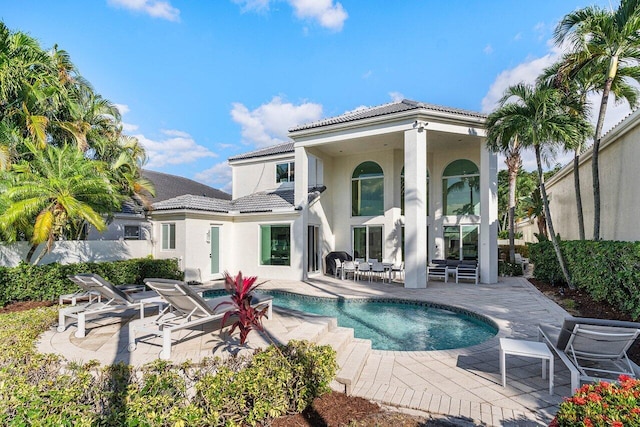 rear view of house featuring a patio and a fenced in pool