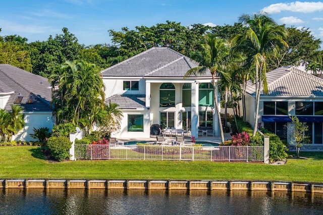 rear view of house with a lawn, a fenced in pool, a water view, a balcony, and a patio