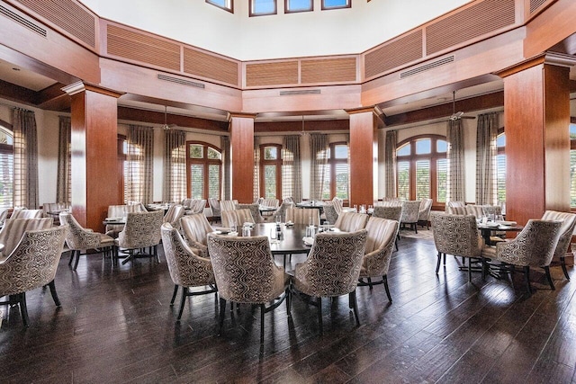 dining room with a towering ceiling, hardwood / wood-style flooring, a wealth of natural light, and wooden walls