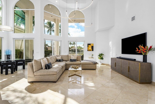 living room featuring a chandelier, french doors, a towering ceiling, and a wealth of natural light