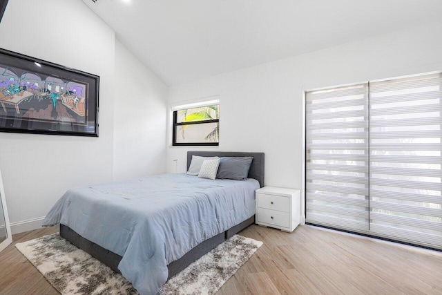 bedroom with light hardwood / wood-style floors and lofted ceiling