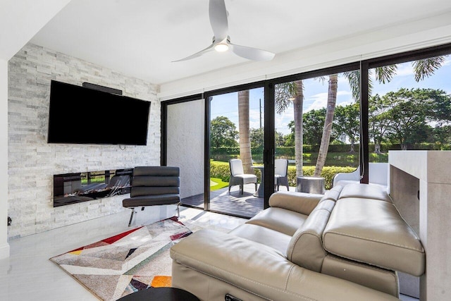 living room featuring a stone fireplace and ceiling fan