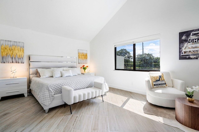 bedroom featuring light wood-type flooring and high vaulted ceiling