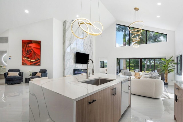 kitchen with pendant lighting, light stone counters, plenty of natural light, and sink