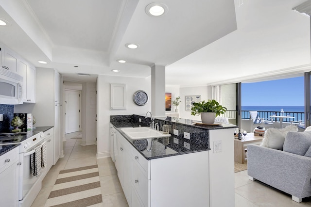 kitchen with sink, a water view, kitchen peninsula, white appliances, and white cabinets