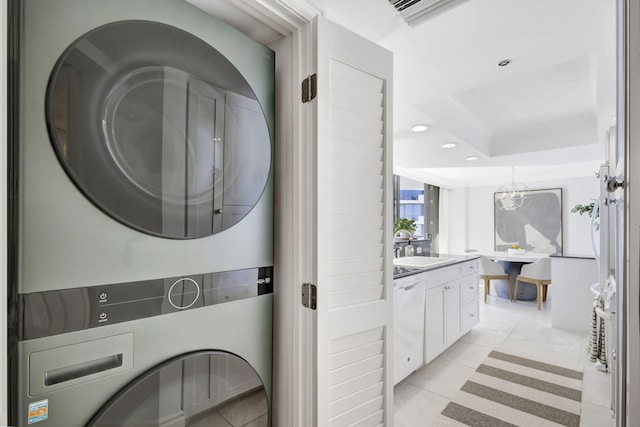 clothes washing area with stacked washer / dryer, sink, light tile patterned floors, and a chandelier