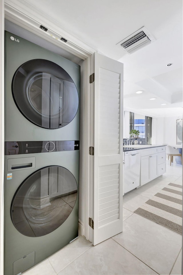 clothes washing area featuring stacked washer and dryer and light tile patterned floors