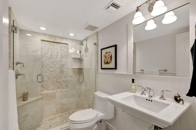 bathroom featuring sink, toilet, and a shower with door