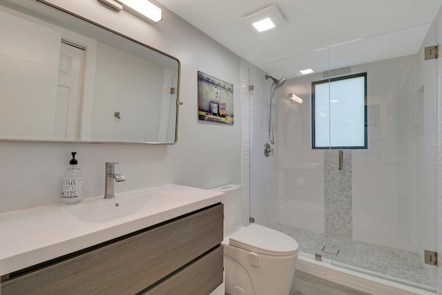 bathroom featuring hardwood / wood-style flooring, vanity, toilet, and a shower with door