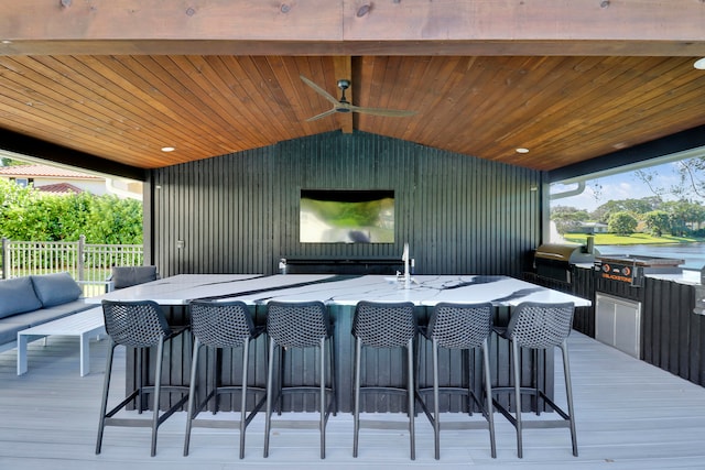 deck featuring ceiling fan, exterior bar, and grilling area