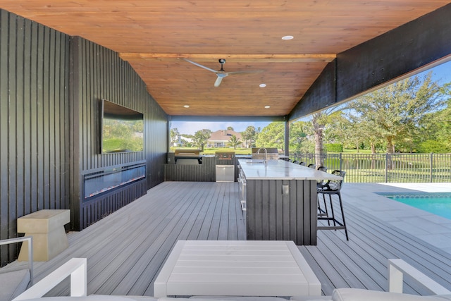 wooden deck featuring ceiling fan, a pool, and exterior bar