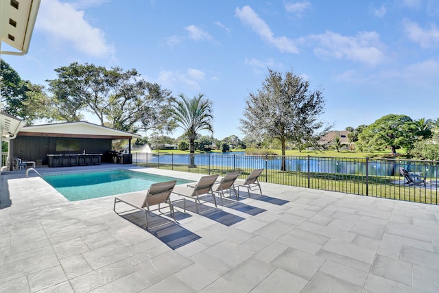 view of swimming pool featuring a patio area, a water view, and exterior bar