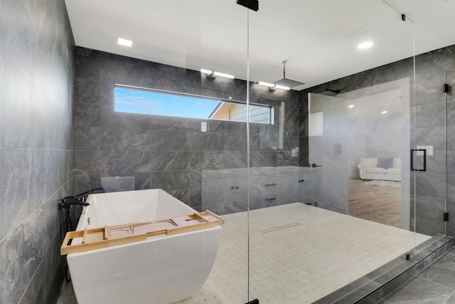 bathroom with tile walls and shower with separate bathtub