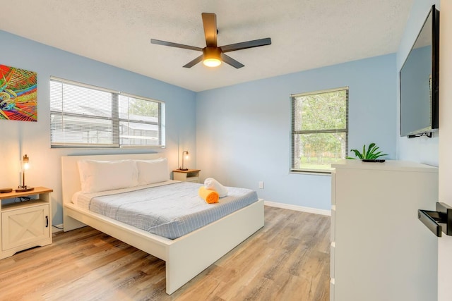 bedroom featuring a textured ceiling, light wood-type flooring, and ceiling fan