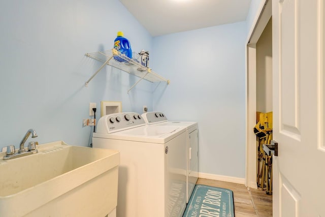 clothes washing area with washing machine and dryer, sink, and light hardwood / wood-style floors