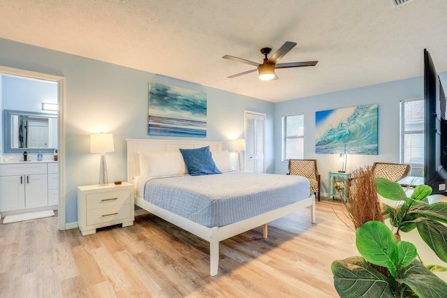 bedroom featuring ensuite bath, ceiling fan, light hardwood / wood-style floors, a textured ceiling, and a closet