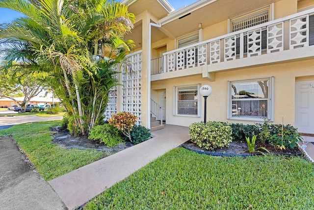 view of exterior entry with a yard and a balcony