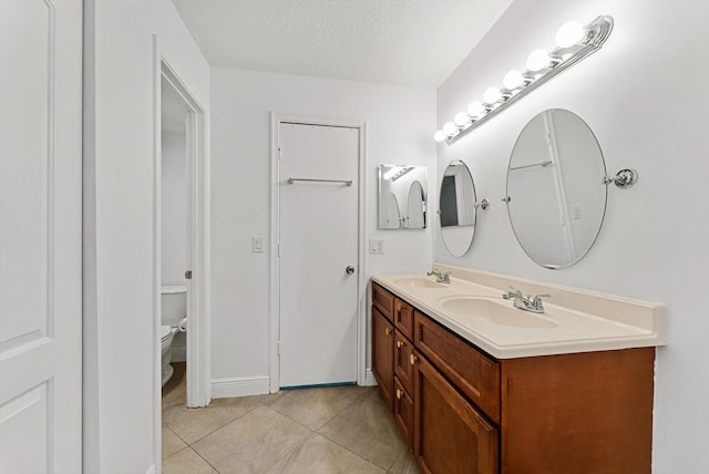 bathroom featuring tile patterned floors, vanity, a textured ceiling, and toilet