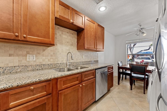 kitchen featuring decorative backsplash, light stone countertops, ceiling fan, sink, and dishwasher