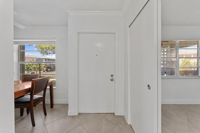 entryway with light tile patterned floors and ornamental molding