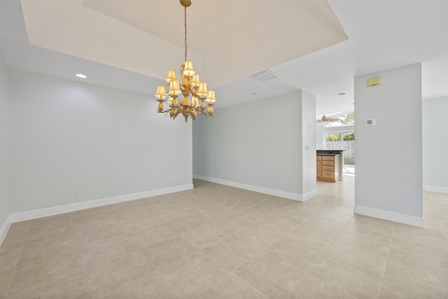 tiled empty room featuring a chandelier and a raised ceiling