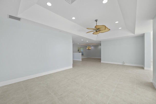 unfurnished living room featuring ceiling fan with notable chandelier, a raised ceiling, and light tile patterned floors