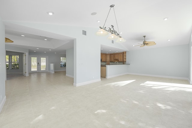 unfurnished living room with ceiling fan, vaulted ceiling, light tile patterned floors, and french doors